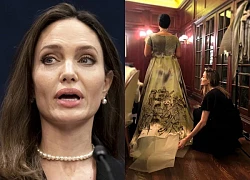 Angelina Jolie with messy hair, kneeling down and lifting the skirt of a star?